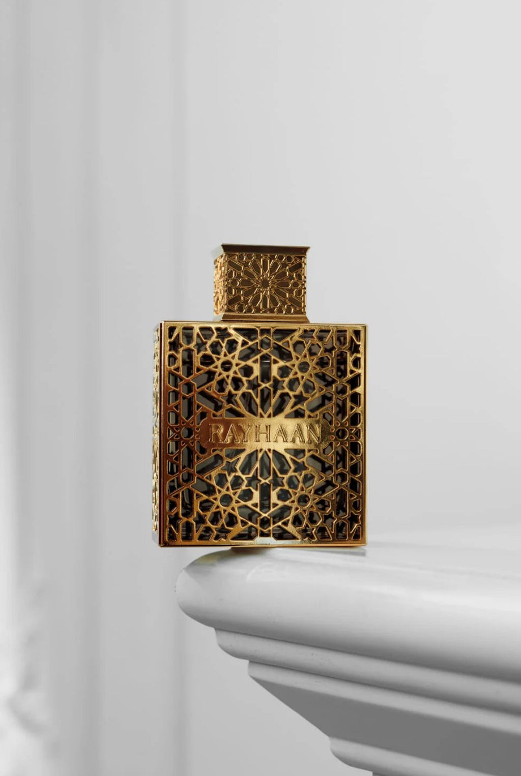 Gold perfume bottle with intricate design on a white background