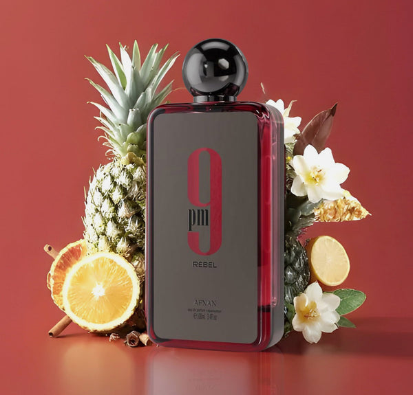9pm Rebel by Afnan 100 ml EDP perfume bottle surrounded by pineapple, orange, and floral notes, highlighting its fruity and zesty fragrance.