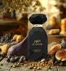 Black perfume bottle labeled 'Al Noor' surrounded by fruits and vegetables on a wooden surface.