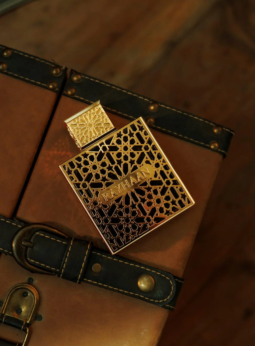 Gold perfume bottle with intricate design on a wooden surface