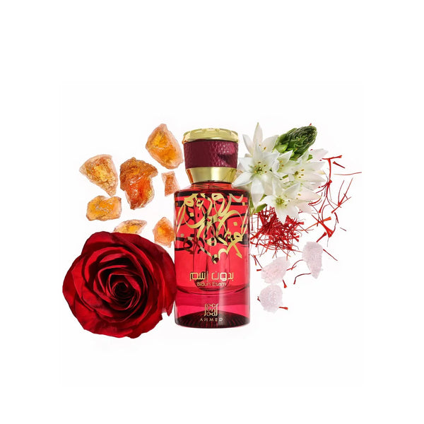 Red perfume bottle with gold cap surrounded by a red rose, amber stones, and white flowers on a white background