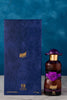 Perfume bottle with purple cap and rose design next to its packaging on a blue background
