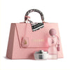 Pink handbag with 'Laverne' branding, featuring a pink perfume bottle and white jar on a light pink background.