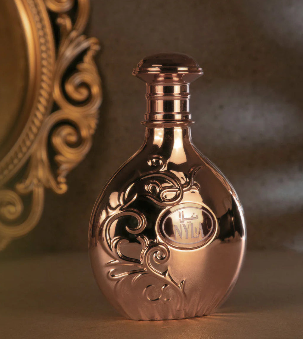 Nyla by Arabiyat Prestige 80ml EDP in a glossy gold bottle with embossed floral design, styled in a warm, luxurious setting for premium appeal.