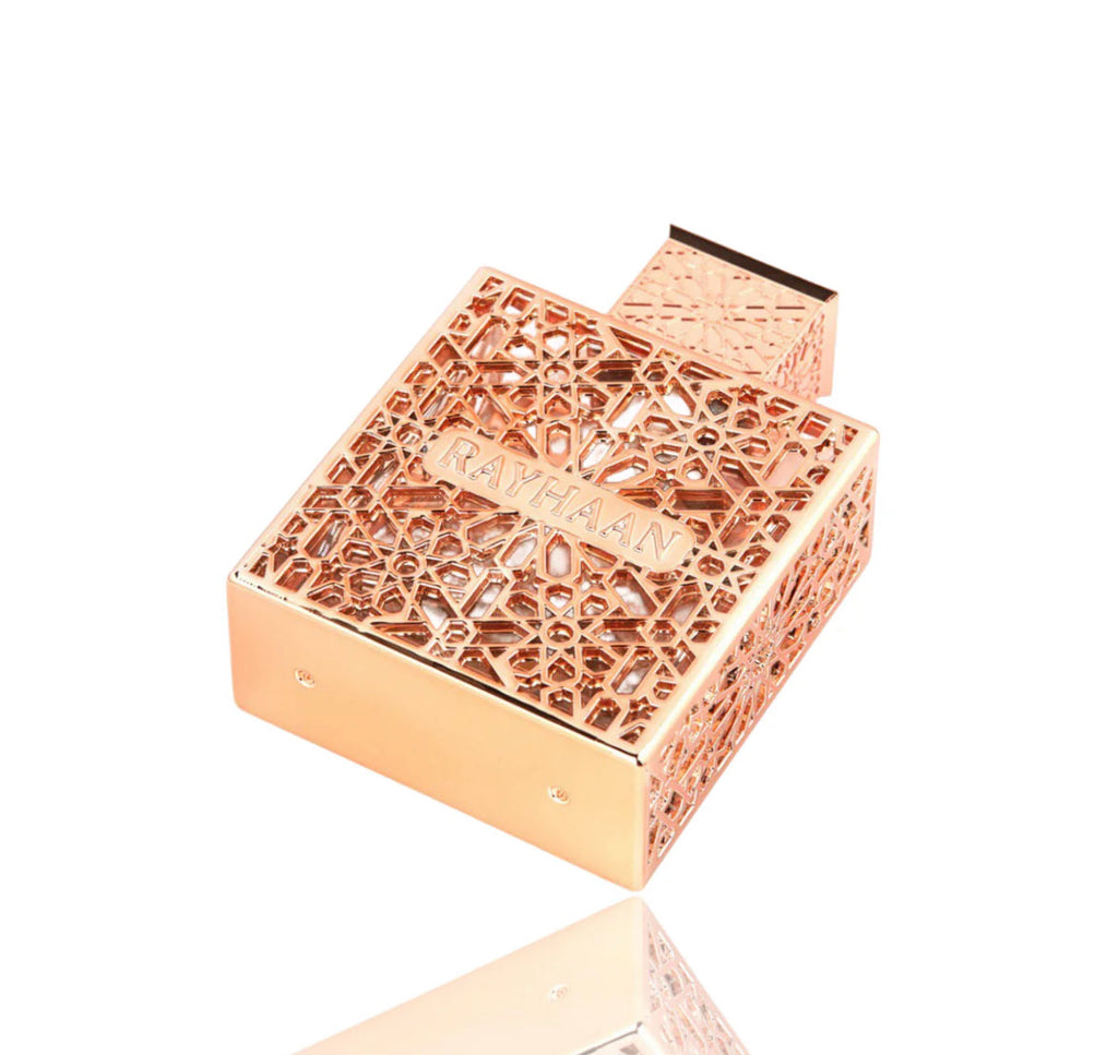 Rose gold perfume bottle with intricate design on a white background
