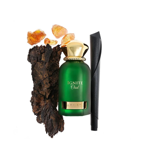 Green perfume bottle with gold cap and label, surrounded by amber stones and a black stick on a white background.